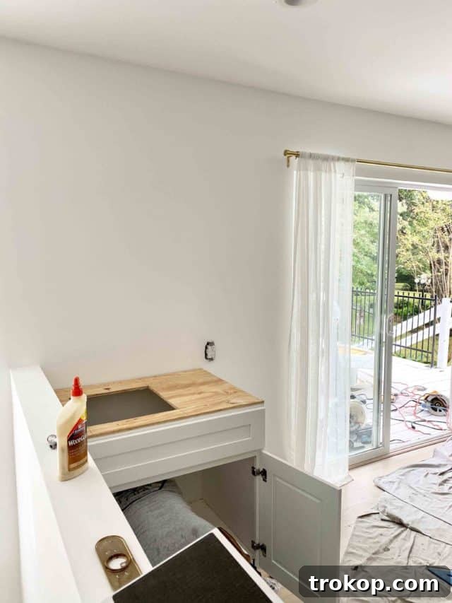 Photo of renovation progress, showing newly installed shaker cabinets and sink in the wet bar