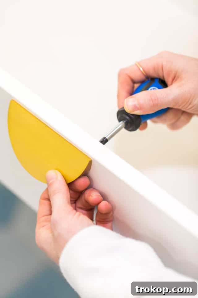 Installing elegant half-moon drawer pulls onto the IKEA Eket vanity, a key step in personalizing the hack.