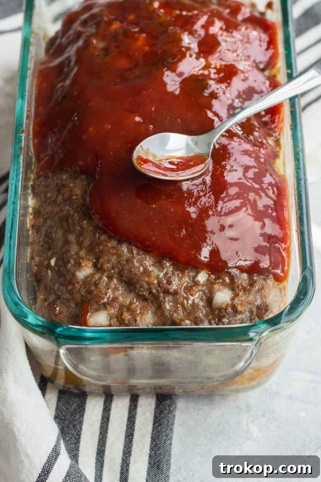 The Ultimate Comfort Meatloaf 7 Meatloaf being covered with sauce before baking