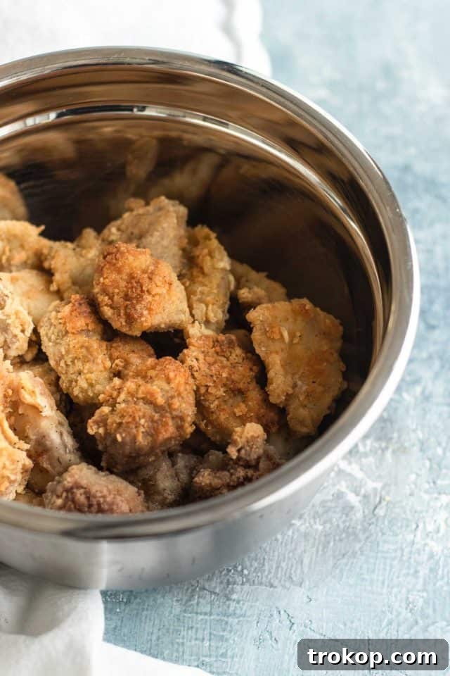 Zesty Orange Chicken 5 First step of cooking the easy orange chicken, showing chicken pieces being dredged in flour mixture, by top Houston lifestyle blogger Ashley Rose of Sugar & Cloth.