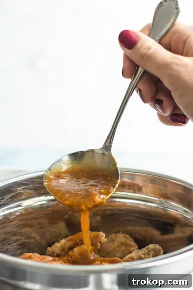 Zesty Orange Chicken 6 Close-up photo of the vibrant orange chicken sauce simmering in a saucepan, ready to coat the crispy chicken, by Houston lifestyle blogger Ashley Rose of Sugar & Cloth.