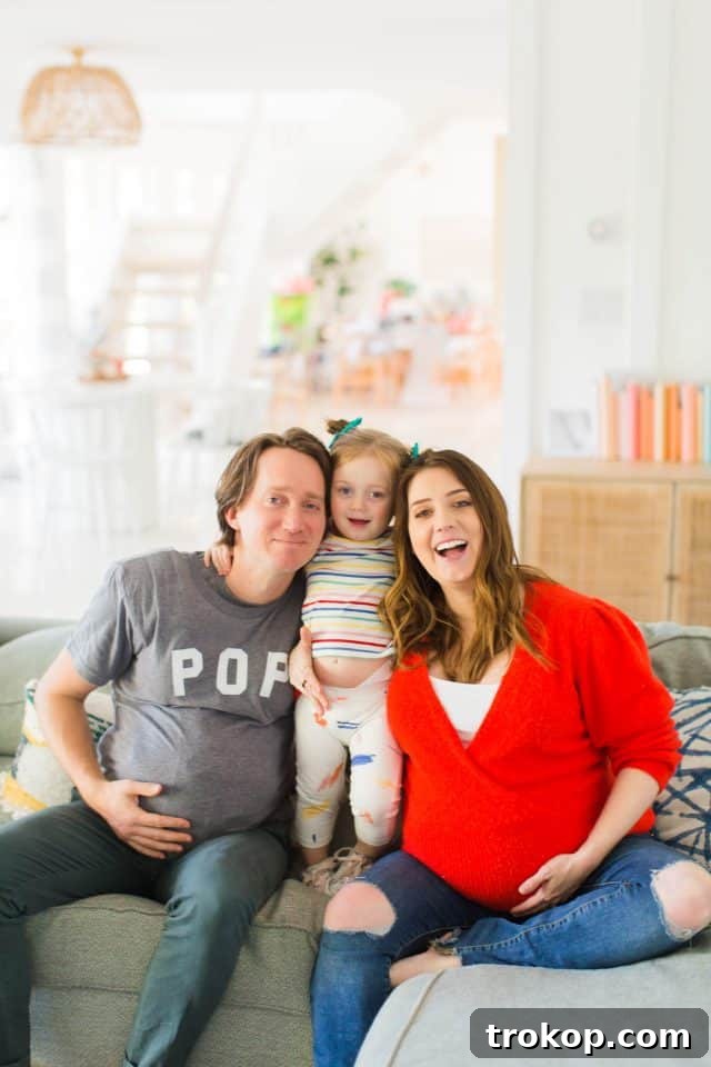 family photo on the couch at 35 weeks, smiling at the camera