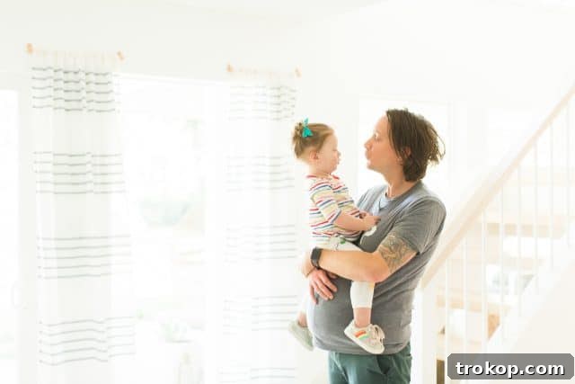dad wearing a fake pregnant belly holding daughter, both smiling