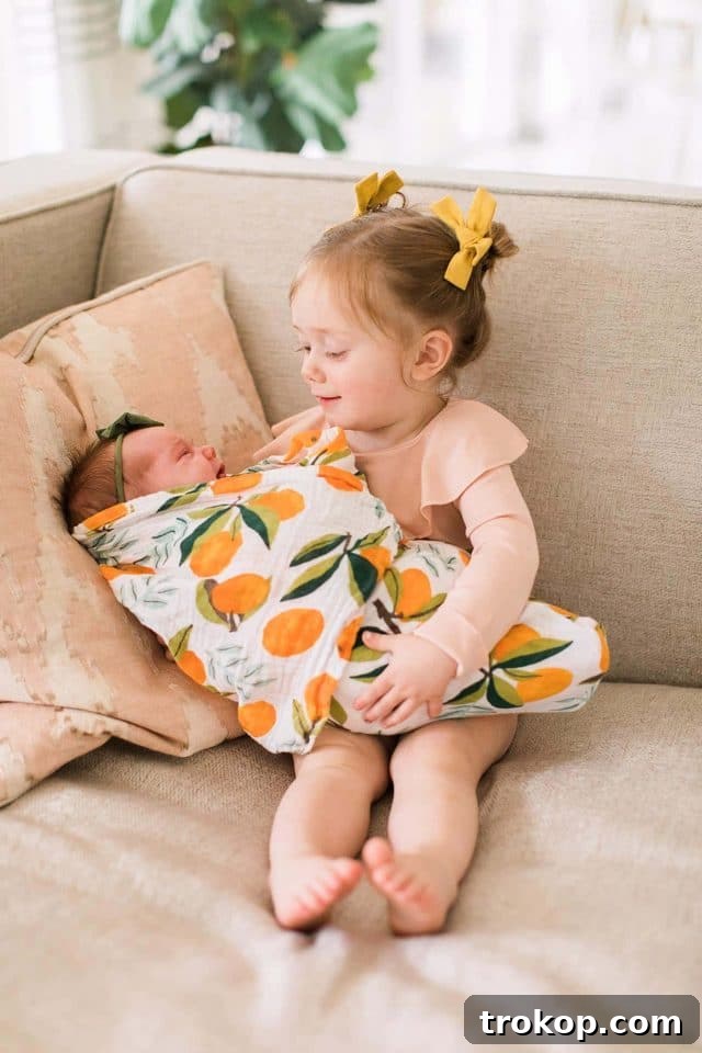 Luca's Newborn Journey: Our Favorite Captures 23 Toddler girl Gwen gently holding her new baby sister Luca, a precious sibling moment