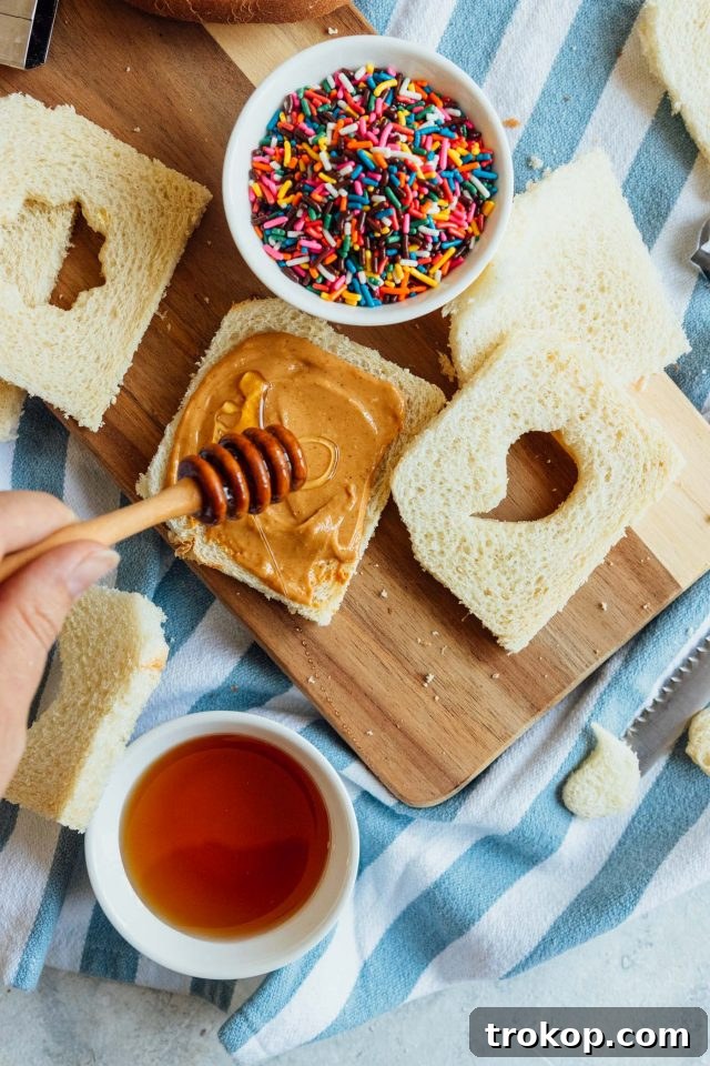 Whip Up Whimsical Fairy Bread 3 A step-by-step photo demonstrating how to spread peanut butter on bread, a crucial first step in making the fairy bread sandwich.