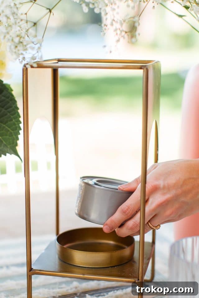 A hand carefully placing a Sterno gel can inside a brass lantern on an outdoor table, ready to repel flies.