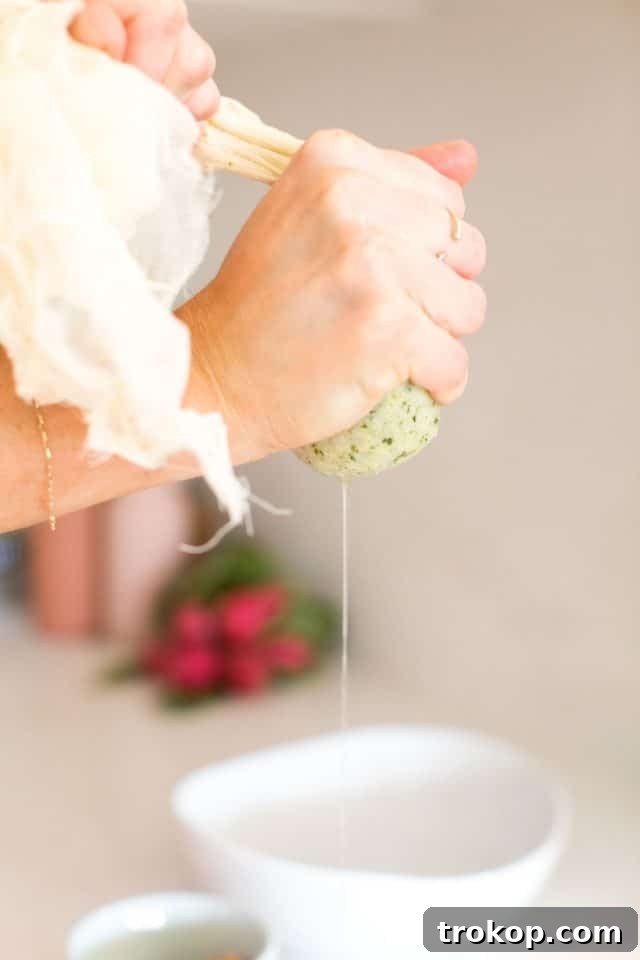 Guilt-Free Cauliflower Pizza Crust for Your Low-Carb Lifestyle 7 Hands squeezing excess liquid from steamed cauliflower florets using a cheesecloth