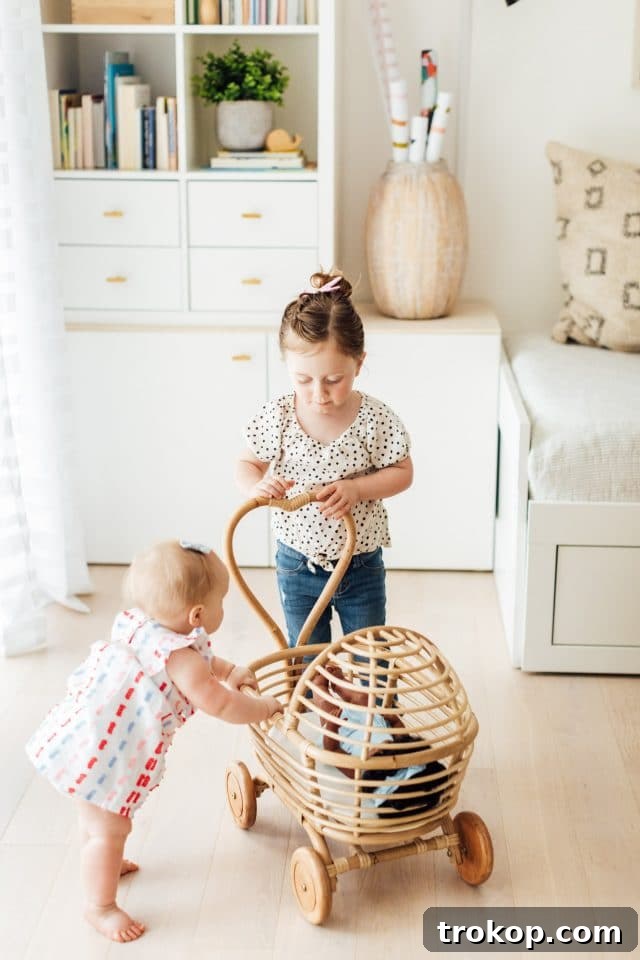 Playroom Makeover: DIY Faux Built-In Cabinets for Organized Fun 8 Little girls playing with a rattan doll cart in a beautifully designed playroom