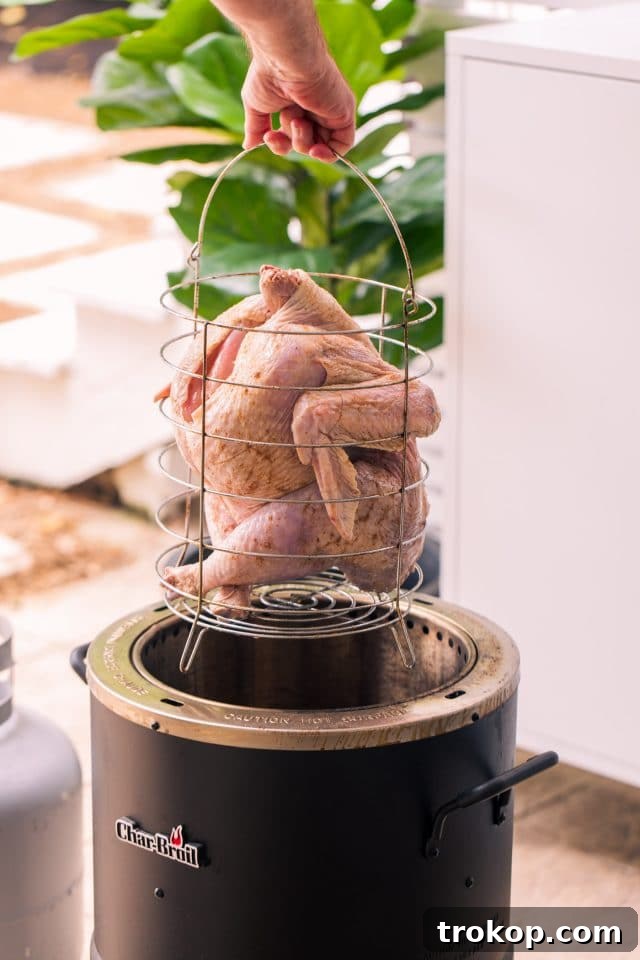 Placing a whole seasoned turkey into an oil-less air fryer, ready for cooking.