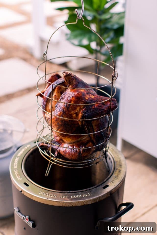 A golden-brown air fryer turkey being carefully removed from the fryer basket, ready for resting.