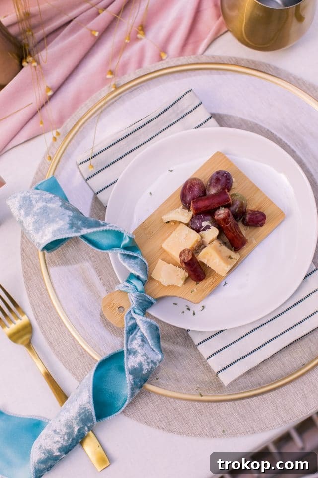 A mini personal cheese plate featuring Belcampo beef sticks, grapes, and cheese, set at a Thanksgiving table setting.