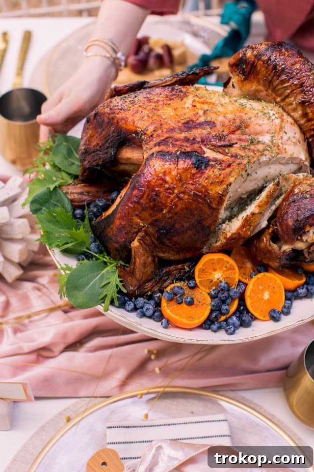 A close-up of hands carefully placing a cooked turkey onto a festive Thanksgiving table, surrounded by decor.