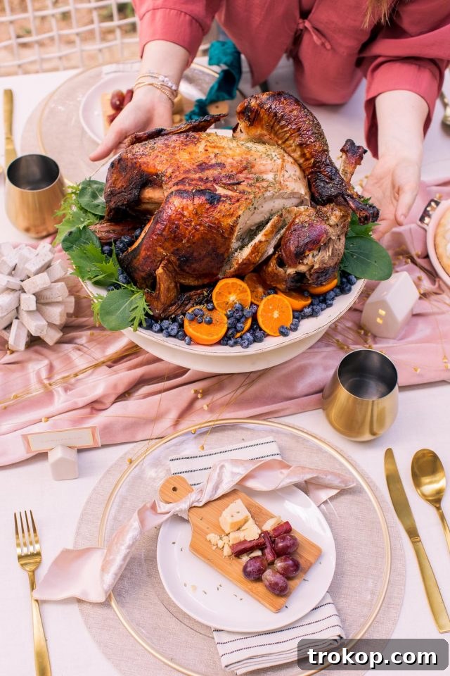 A close-up shot of a golden-brown air fryer turkey, showcasing its crispy skin, next to a variety of festive appetizers on a Thanksgiving spread.
