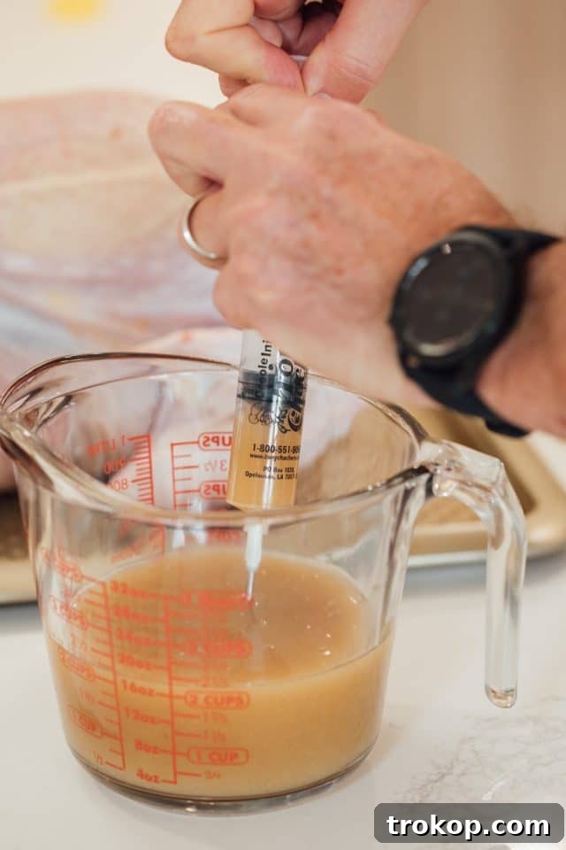 A hand using an injector to infuse the turkey breast with Tony Chachere's Injectable Butter Marinade.
