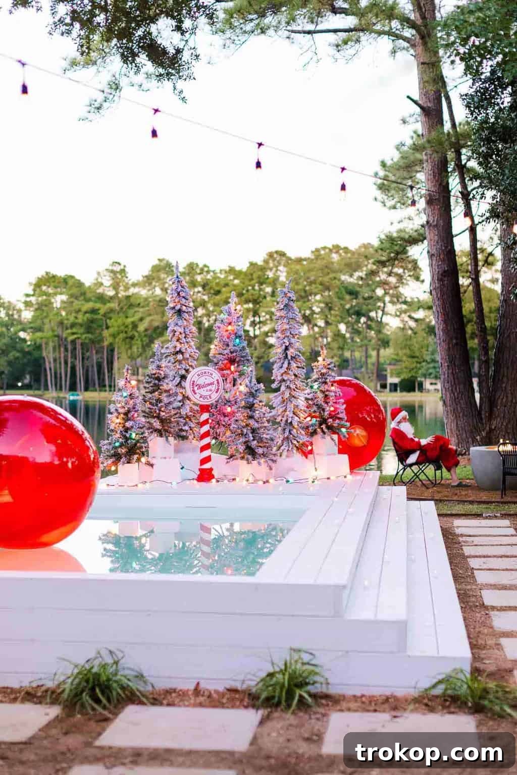 Santa's Poolside Paradise Christmas 8 A charming 'Santa Parking' sign placed amidst a beautiful outdoor Christmas display on a pool deck, surrounded by flocked trees and lights.