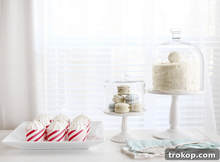 An array of festive holiday desserts presented on elegant cake stands and served in candy-striped muffin cups, central to the Sugar & Cloth holiday celebration.
