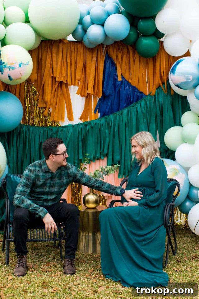 Your Essential Guide to a Drive-Thru Baby Shower 11 A mom and dad-to-be comfortably seated at a beautifully decorated drive-thru shower backdrop, surrounded by giant balloons and celebratory decor