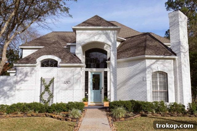 a horizontal photo of a beautifully painted white exterior brick house with limewash