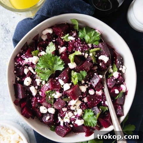A healthy beetroot salad with goat cheese, parsley, and a lemon vinaigrette dressing, presented in a bowl.