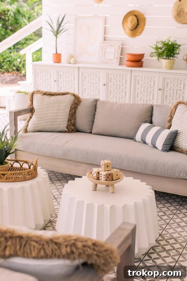 Two white geometric concrete tables in front of an outdoor sofa on the new tiled patio