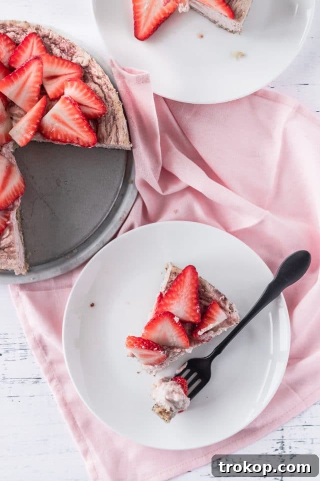 A vibrant, whole low-carb strawberry cheesecake, beautifully garnished with fresh strawberries on top, set against a bright background, ready to be served.