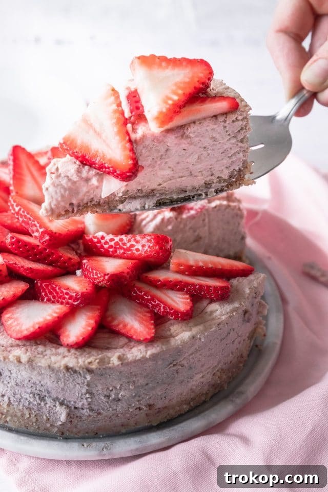 A slice of keto strawberry cheesecake being served on a plate, highlighting its creamy texture and strawberry swirl, suggesting readiness for enjoyment.