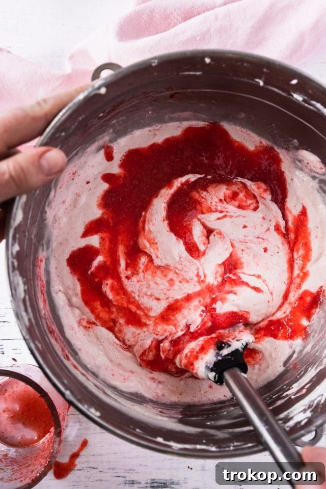 A close-up photo showing the creamy cheesecake filling being prepared in a stand mixer, with the paddle attachment ensuring a smooth consistency.