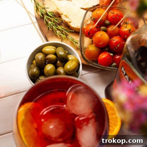 A glass of Martini Fiero with an orange slice, next to a fruit platter.