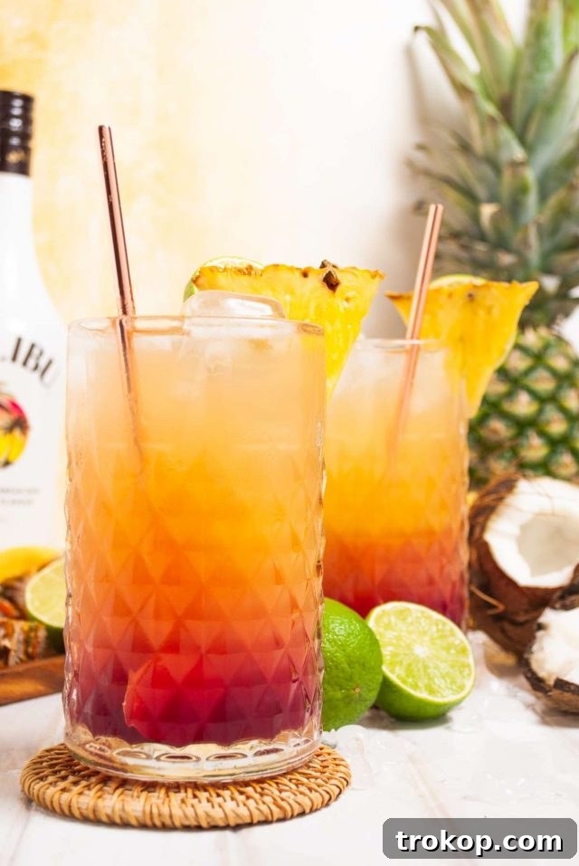 Perfect Tropical Malibu Bay Breeze Mix 2 Malibu Bay Breeze cocktail in a glass, surrounded by coconut and lime slices, evoking a tropical island vibe, perfect for a sunny day.