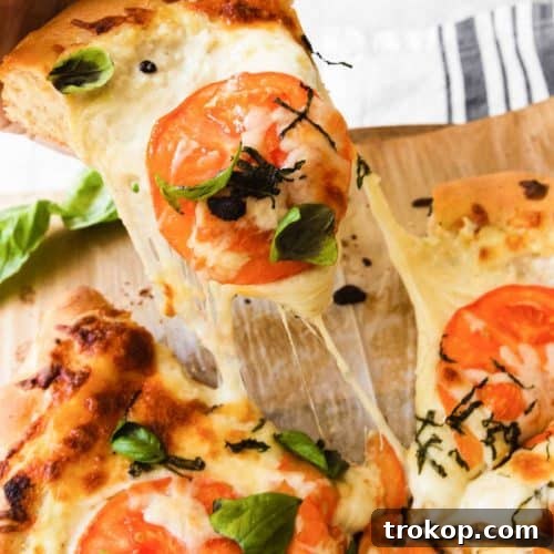 Creamy White Sauce Pizza 12 A hand grabbing a single slice of white pizza, showcasing its golden crust