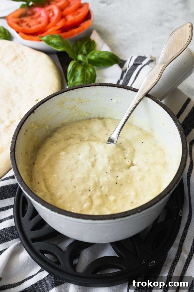 Creamy White Sauce Pizza 4 White pizza sauce simmering in a saucepan, showing its creamy texture