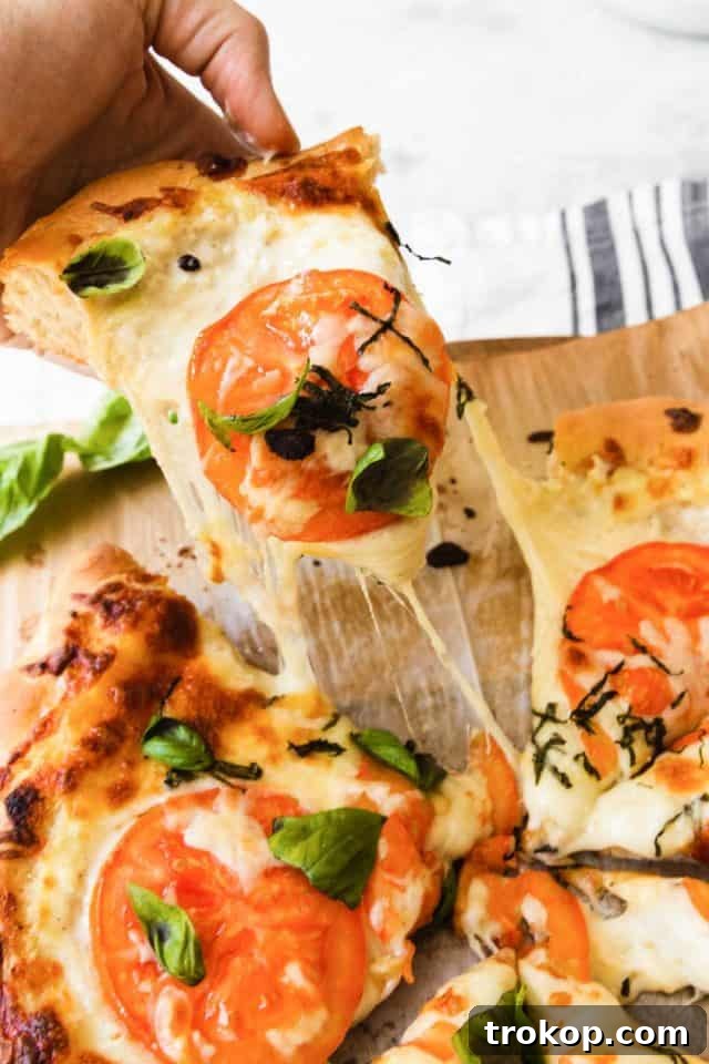 Creamy White Sauce Pizza 6 A hand reaching for a slice of freshly baked white pizza with golden crust