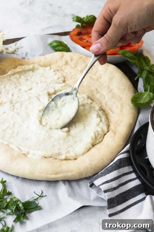 Creamy White Sauce Pizza 8 Spreading creamy white sauce onto a pizza dough