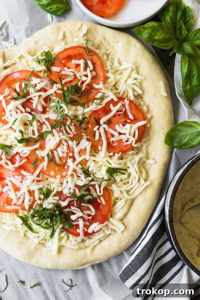 Creamy White Sauce Pizza 10 Overhead view of a raw white pizza with cheese and toppings before baking