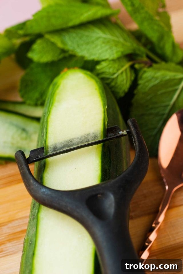 martini extra dry - a potato peeler expertly peeling a cucumber to create elegant cucumber ribbons for garnish for the Martini Spritz