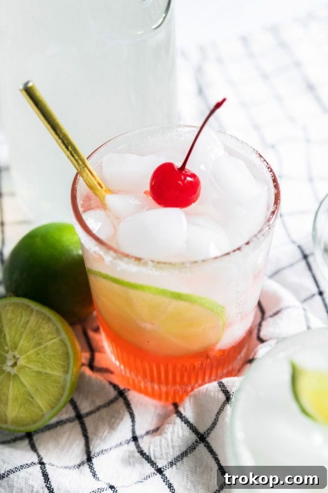Refreshing Homemade Limeade 9 A single serving of cherry limeade, showcasing its vibrant color and a fresh cherry garnish.