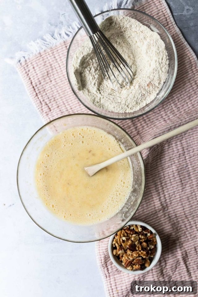 Separate bowl with dry ingredients (flour, baking soda, baking powder, salt, cinnamon, nutmeg) being whisked.