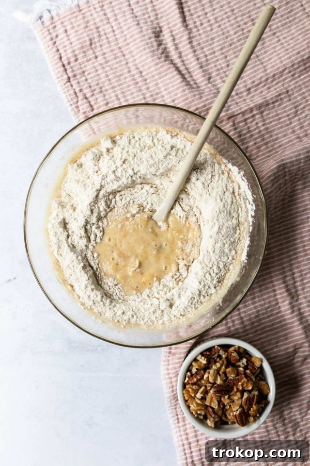 Banana bread batter in a bowl with nuts partially mixed in.