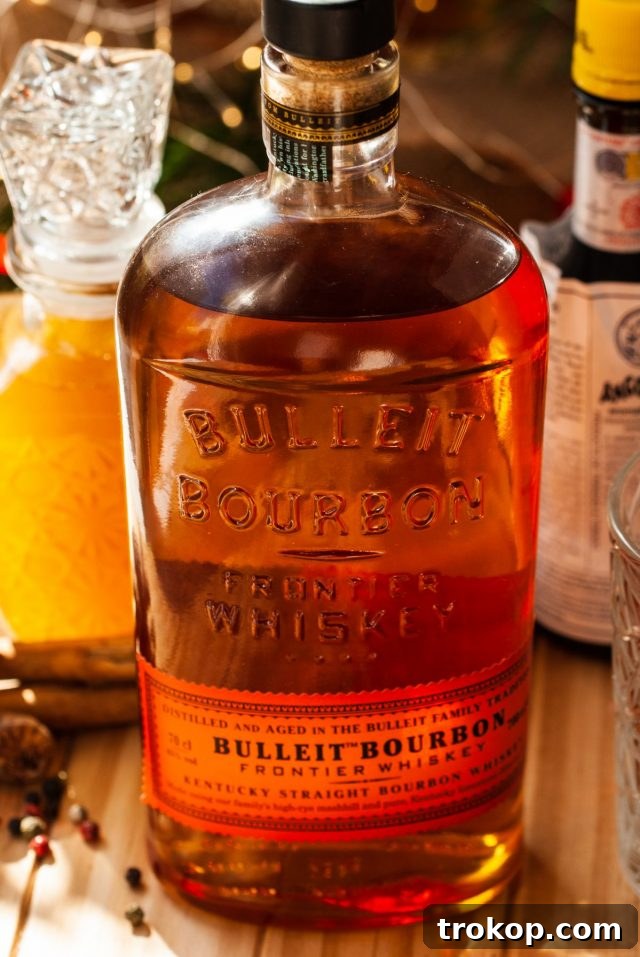 Heirloom Christmas Recipes 3 Bulleit Bourbon bottle next to a glass of Christmas Old Fashioned, showcasing the quality ingredients.