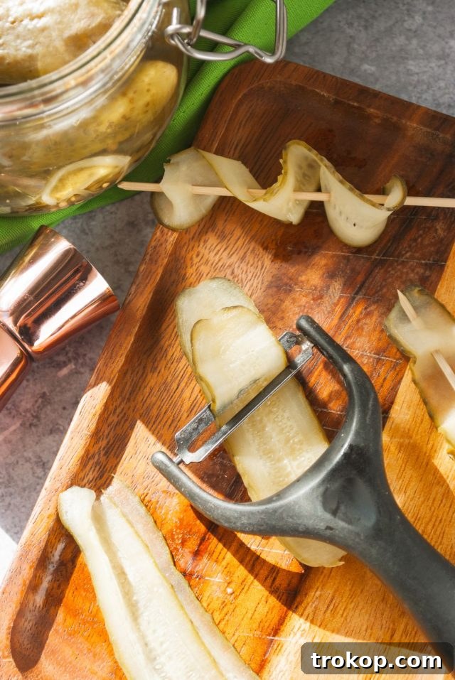 A potato peeler being used to create thin strips of pickle for a cocktail garnish.
