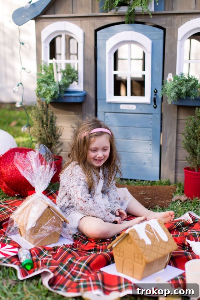 Close-up of a child decorating a gingerbread house kit inside the festive playhouse