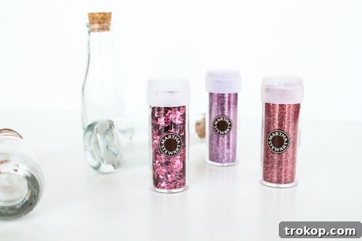 Three mini love potion bath bottles with glitter corks arranged on a white surface