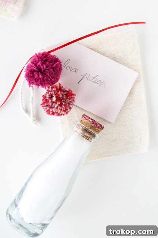 Collection of finished DIY love potion bath sets in various bottles with glitter corks and tags, ready for gifting