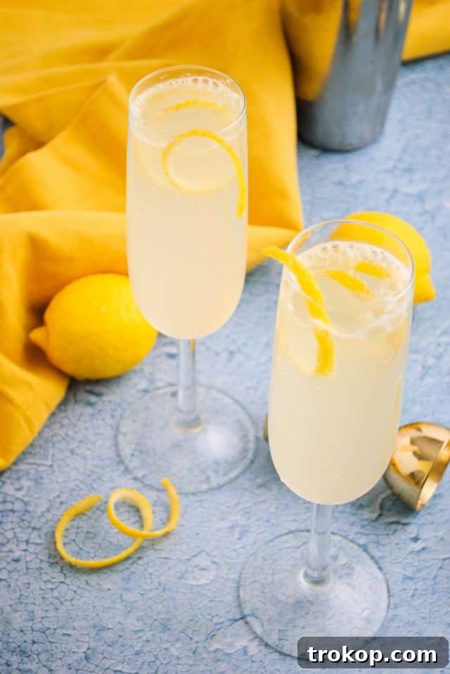 French 76 cocktail - two elegant champagne glasses filled with the golden bubbly drink, garnished with lemon twists.
