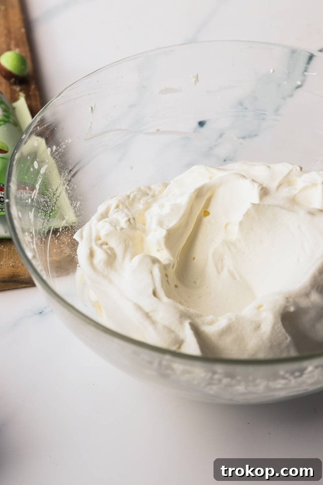 Close-up of fluffy cream cheese and sugar mixture being beaten in a large bowl