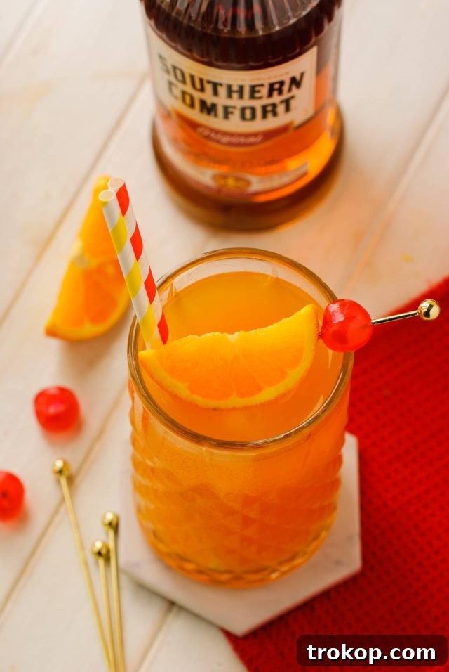 alabama slammer with cocktail pick with one orange wedge and a maraschino cherry