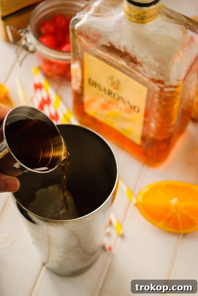 adding liquor in a cocktail shaker for the alabama slammer