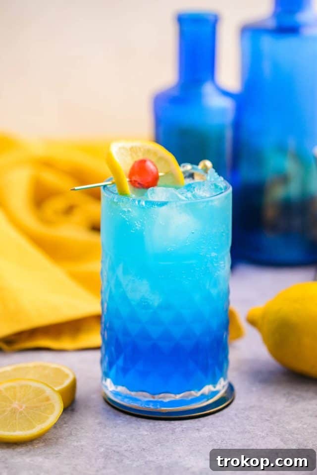 Classic Blue Motorcycle cocktail in a tall glass, garnished with a lemon wheel and a cherry