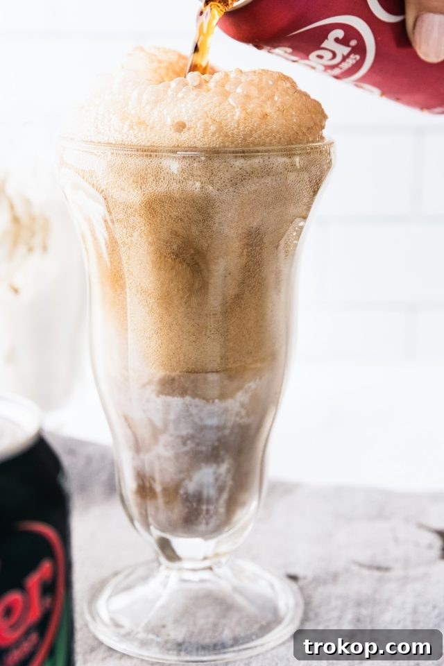Decadent Homemade Dr. Pepper Vanilla Float 9 Close-up photo of a Dr. Pepper Vanilla Float being topped off with a generous swirl of whipped cream