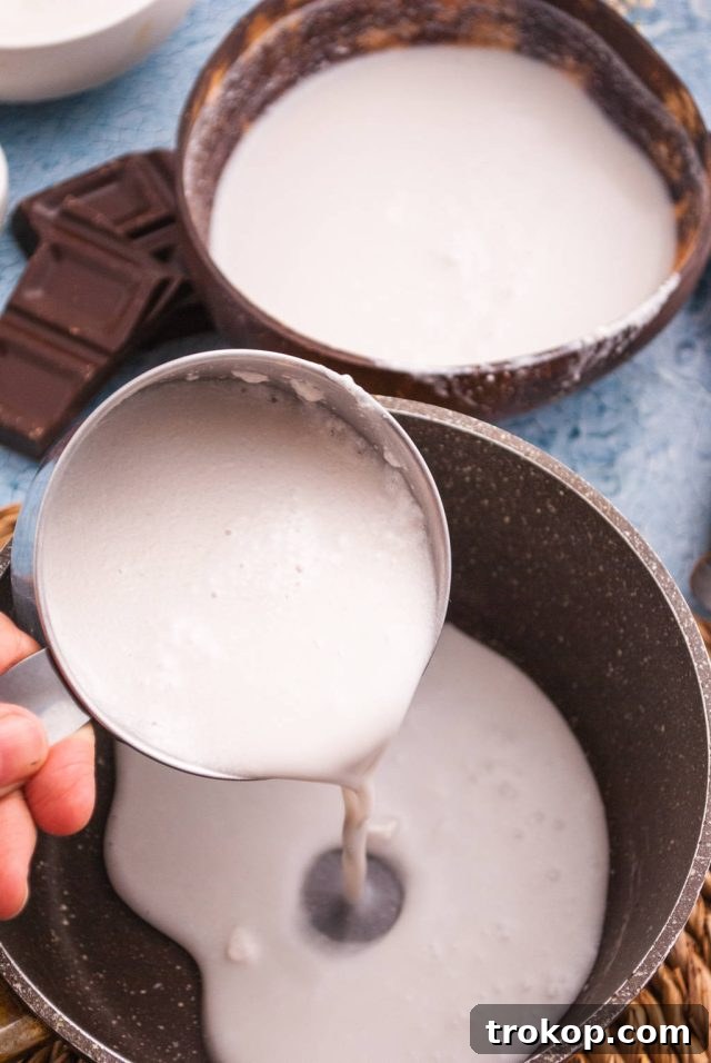 Bushwacker Recipe: Make Your Own Cream of Coconut Cocktail 4 Adding full-fat coconut milk, granulated white sugar, and a pinch of salt to a saucepan to prepare homemade cream of coconut for tropical cocktails.